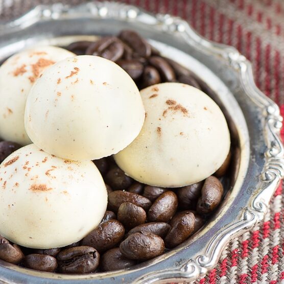 Cappuccino truffles sitting on a bowl of coffee beans